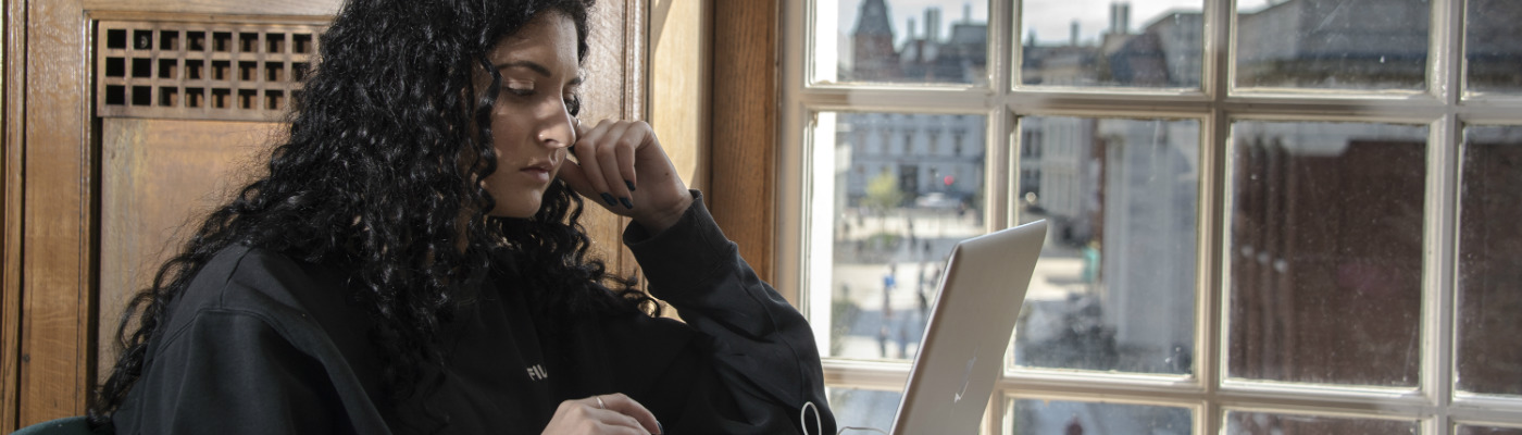 female on laptop by window